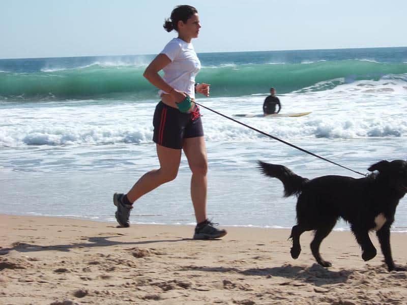 a woman running on the beach with her dog