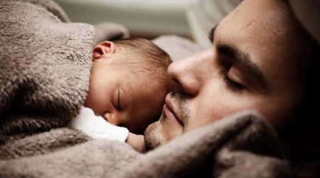 Man snuggling newborn
