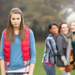 Upset Teenage Girl With Friends Gossiping In Background