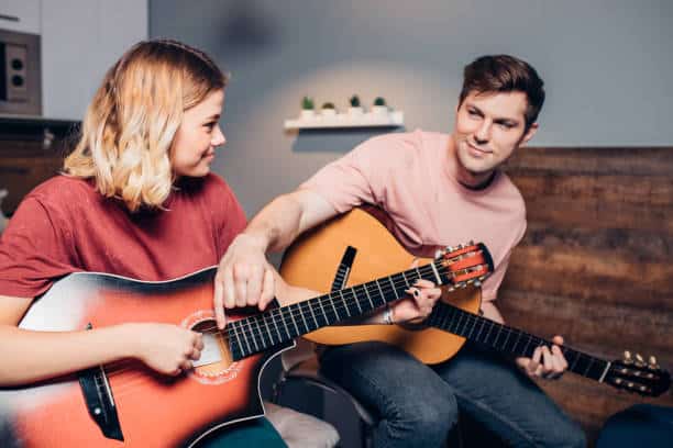 Two friends play guitar together. A hobby is one of the best coping skills for depression.